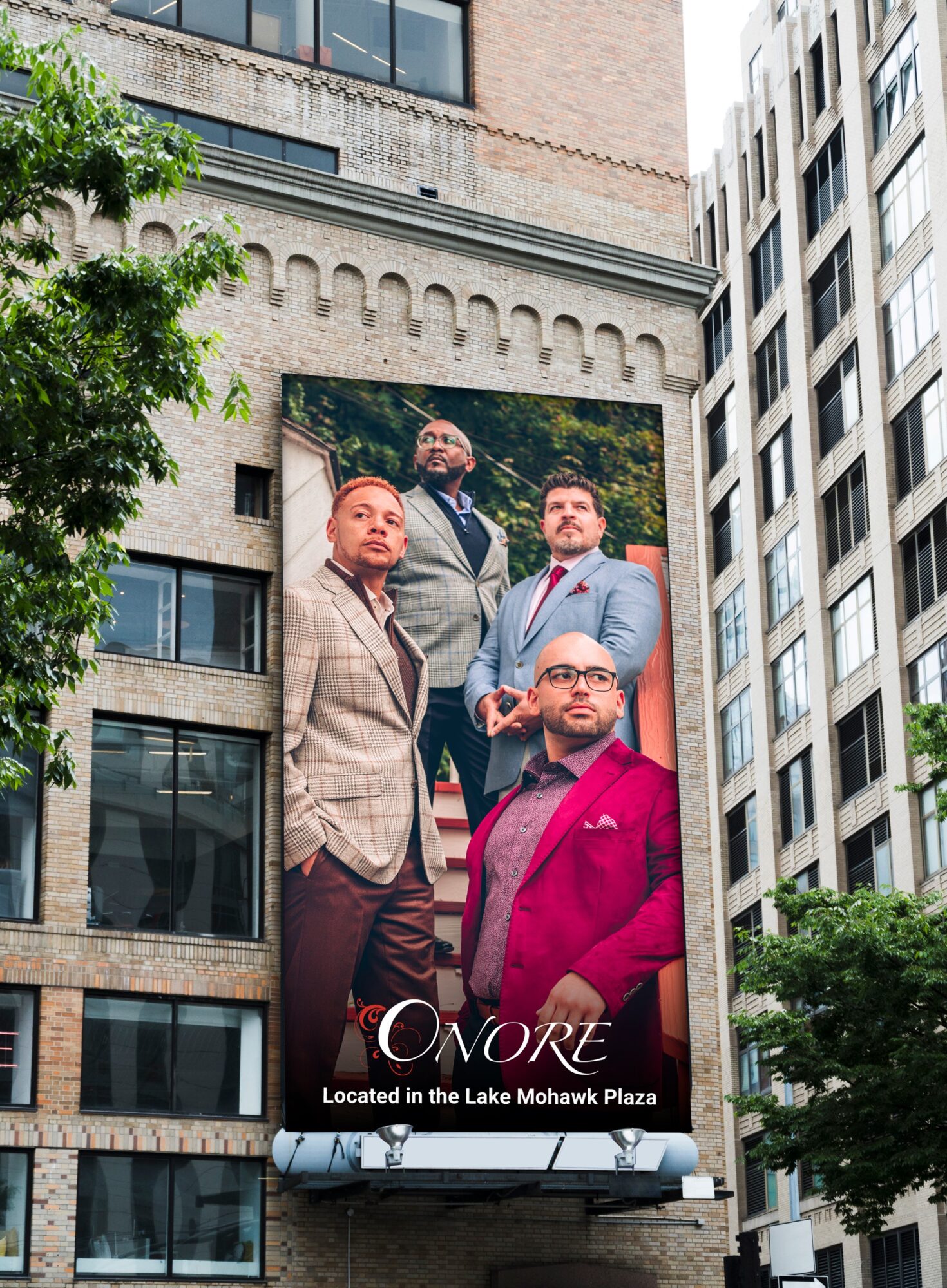 Large billboard featuring four men in suits, with text indicating location at Lake Mohawk Plaza.