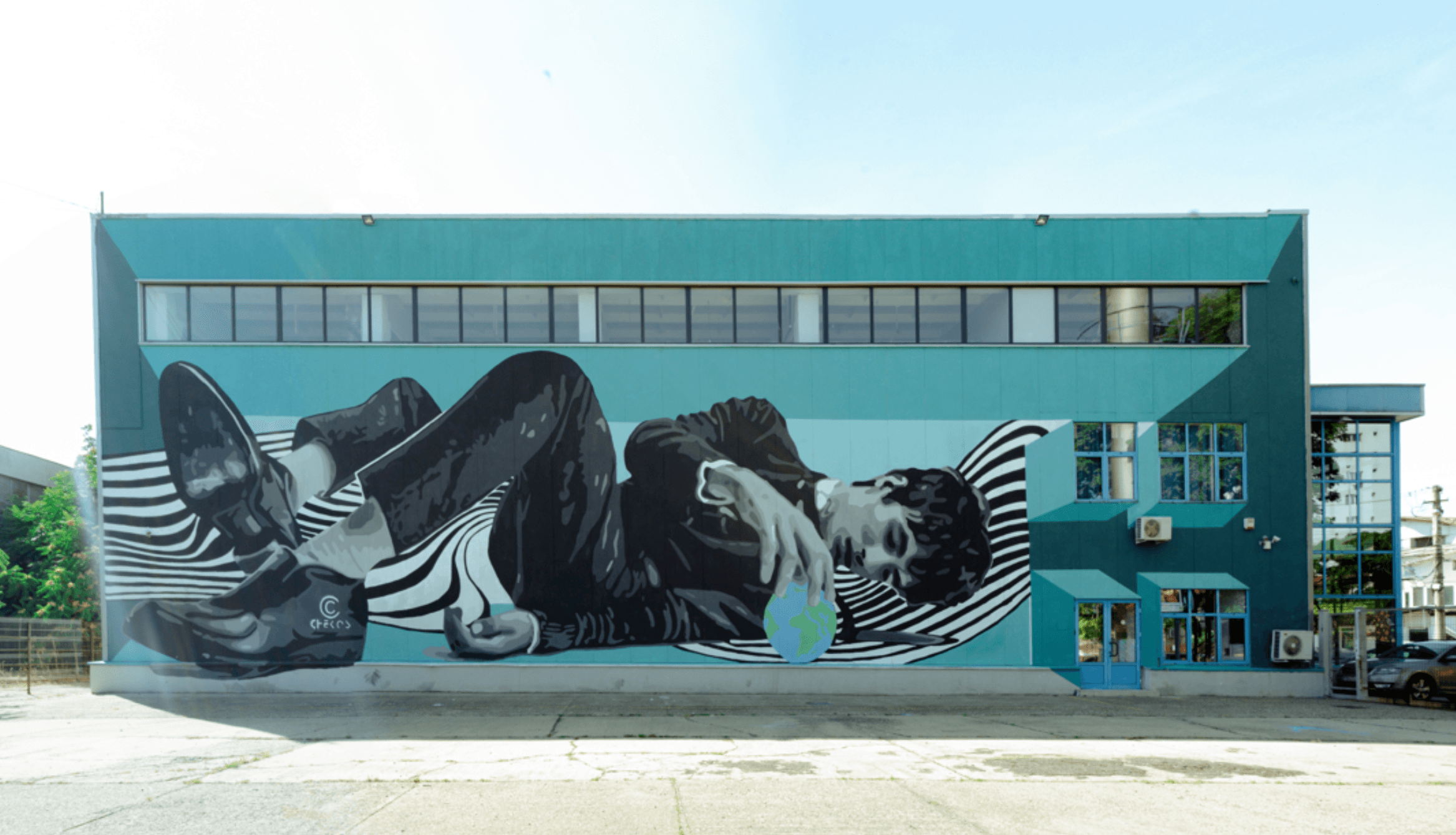 A large black-and-white mural covers the turquoise facade of a modern building.