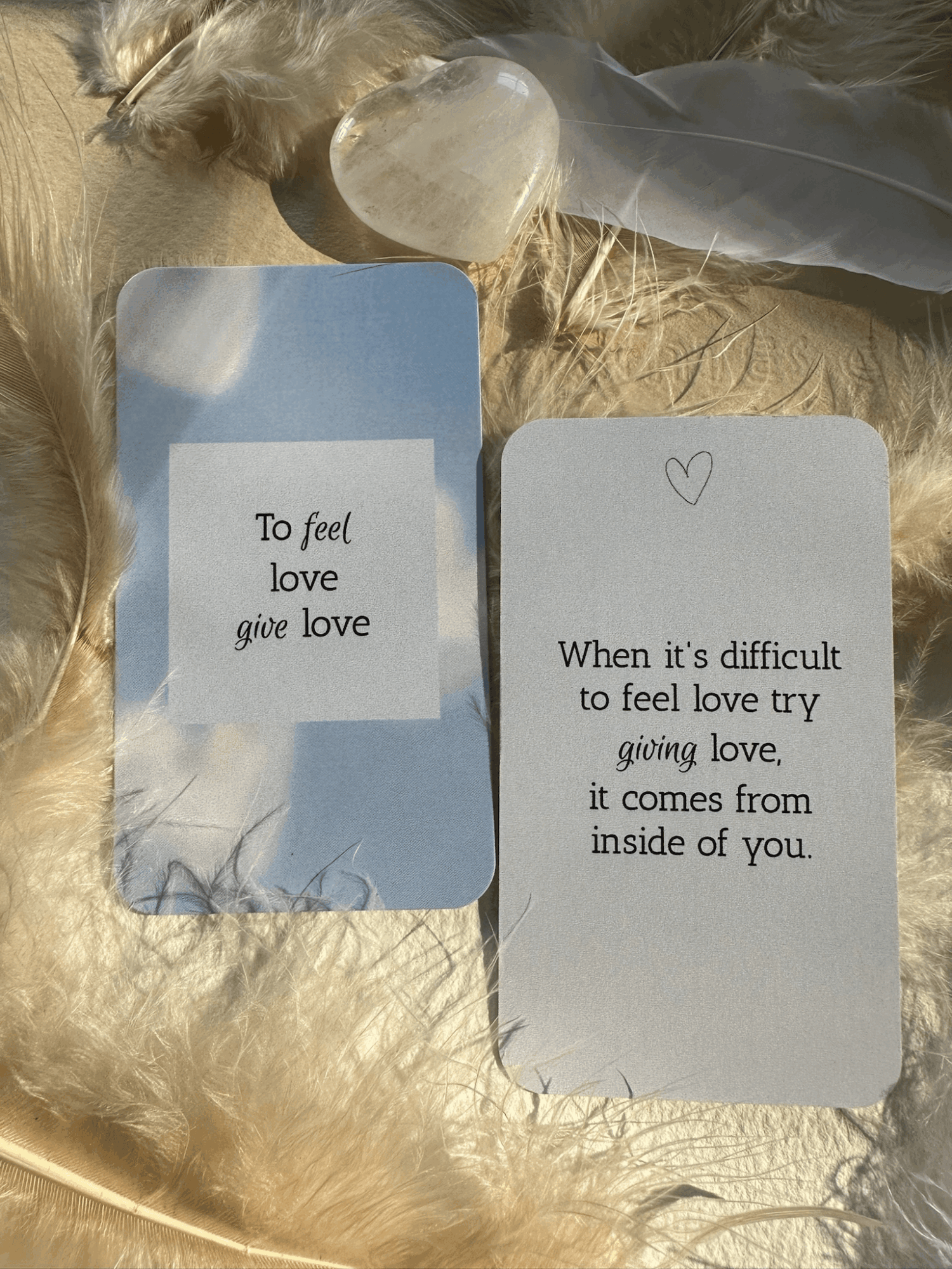 Two cards with handwritten messages rest on cream fabric beside a translucent stone and dried grasses.
